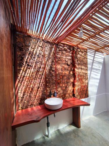 a bathroom with a wooden wall with a sink at Likat Surf House in Tua Pejat