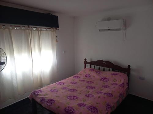 a bedroom with a bed with a pink comforter and a window at Descanso LA MARTA in Pueblo Esther