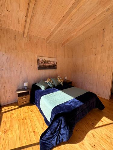 Un dormitorio con una cama en una habitación de madera. en Cabañas Polikén, en Lago Vichuquen