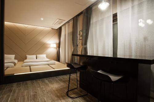 a bedroom with a bed and a desk and a mirror at CS Premier Hotel in Anyang