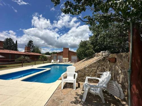 zwei weiße Stühle neben einem Pool in der Unterkunft Shanti Cabañas in Mina Clavero