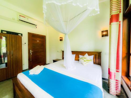 - une chambre avec un lit bleu à baldaquin dans l'établissement Sunworld Villa, à Unawatuna