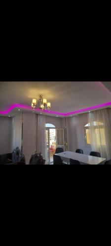 Ein Zimmer mit Tisch und Stühlen und rosa Beleuchtung in der Unterkunft مكان هادي وراقي للاسترخاء in Kafr Mas‘ūd