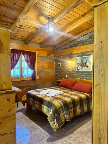 Un dormitorio con una cama en una cabaña de troncos en Cabañas Alvear, en Huerta Grande