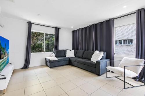 a living room with a couch and some windows at The Arcade Escape - Games & Vibes in Gold Coast