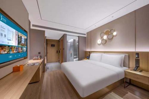 a large bedroom with a large white bed and a tv at Orange Hotel Shenzhen Nanshan Subway Station in Shenzhen