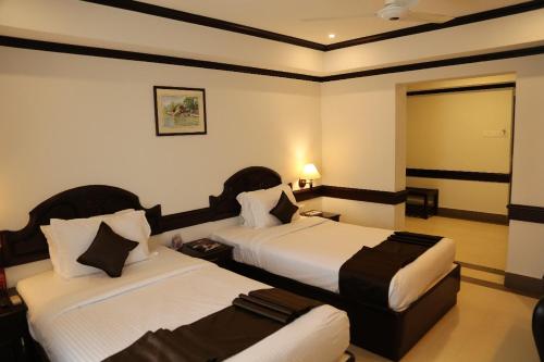 Una habitación de hotel con dos camas y un espejo. en Hotel Aroor RESIDENCY, en Jāmb