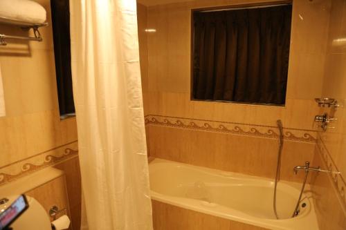 Un baño con bañera y cortina de ducha. en Hotel Aroor RESIDENCY, en Jāmb