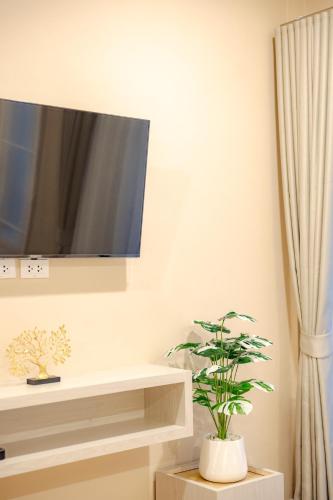 a living room with a tv and a plant at Treerat Bangtao House in Ban Hua Phrong