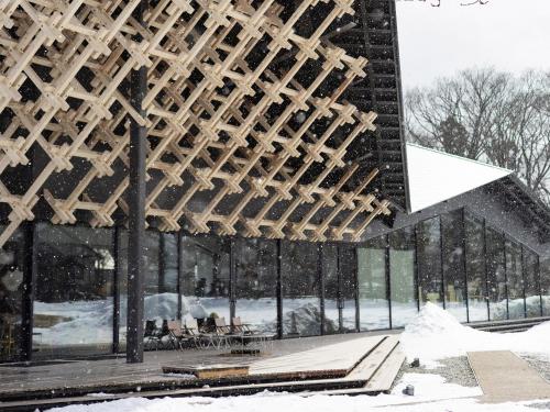 a building covered in snow with a lot of windows at Snow Peak LAND STATION HAKUBA in Hakuba