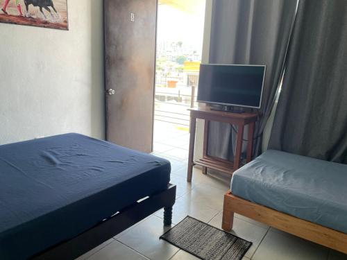 Un dormitorio con una cama y un televisor de pantalla plana. en Hotel Ricarda Yopes, en Acapulco