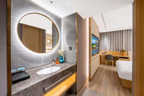 a bathroom with a sink and a mirror at Orange Hotel Shenzhen Nanshan Subway Station in Shenzhen