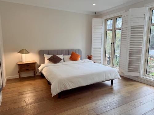 ein Schlafzimmer mit einem großen weißen Bett und einem Fenster in der Unterkunft Hampton Luxe Retreat 4BR Pet Friendly in Melbourne