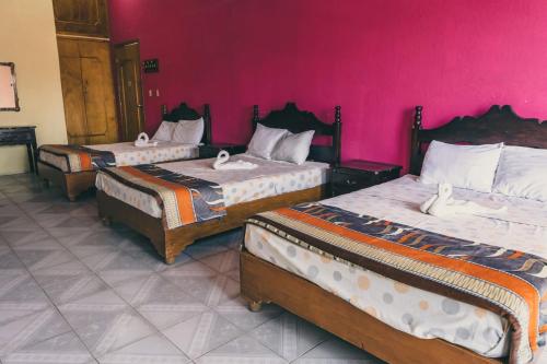 three beds in a room with a pink wall at Hotel Real in Chiapa de Corzo
