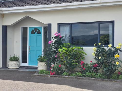 a house with flowers in front of a blue door at Riverstone Retreat Upper Hutt in Upper Hutt