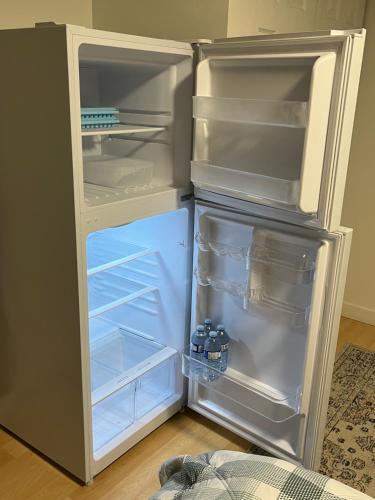 an empty refrigerator with its door open in a room at Cozy Escape in the City in Port Coquitlam