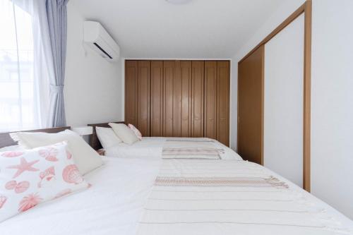 two beds in a bedroom with white sheets and pink pillows at Entire Villa, 2-Min to Beach, near Enoshima Island in Fujisawa