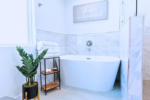 a white bathroom with a tub and a plant at Plano 40 miles to Fifa Stadium Private Pool Lux Home by Vacation Your Way in Plano