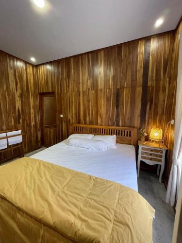 a bedroom with a large bed with wooden walls at Villa Bella Sembalun in Sembalun Lawang