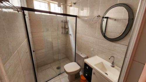 a bathroom with a shower and a sink and a mirror at Pousada da Lua Barretos in Barretos