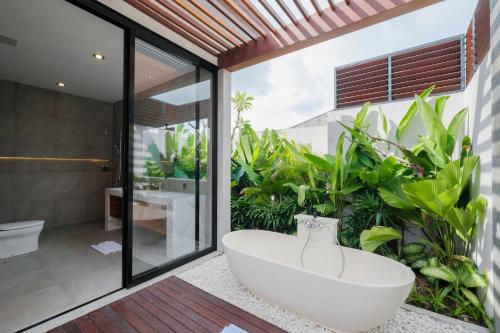 baño con bañera grande y plantas en Three Brothers Munggu Suites Villas and Restaurant, en Pererenan