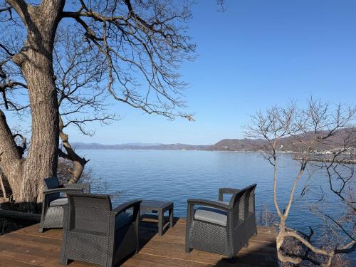 a group of chairs sitting on a wooden deck next to a lake at Toya Tiny Cabin in Lake Toya