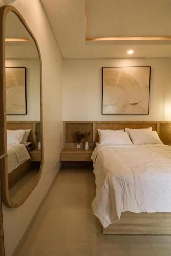 a bedroom with a large bed and a mirror at Giegie Villa in Tanah Lot