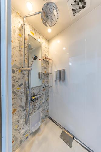 a shower in a bathroom with a stone wall at オーシャンビュー窓から見える景色を思い出に The琉球タワー10F in Yonabaru