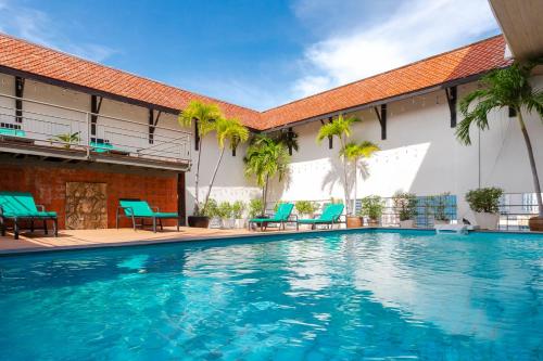 a swimming pool in front of a building with blue chairs at Pinnacle Lumpini Park Hotel in Bangkok