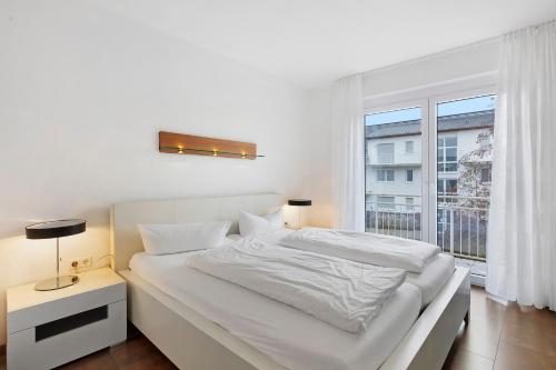 una camera da letto bianca con un letto e una finestra di Markgraf Apartments Haus 2 a Hertingen