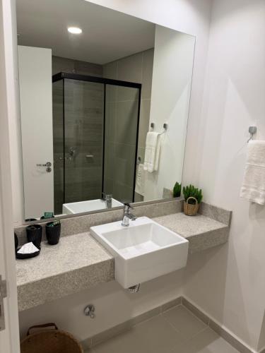 a white bathroom with a sink and a mirror at Vivo Costanera Apartamento Frente a la playa San José de Encarnación! in Encarnación