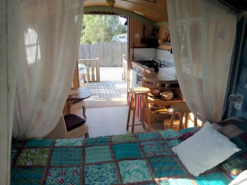 1 dormitorio con 1 cama y cocina con ventana en La Roulotte Daninas, en Villeneuve-en-Retz