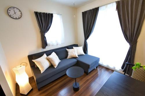 a living room with a blue couch and a clock at Chill Place 125 Kameari in Tokyo