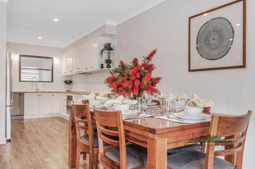 a dining room with a table and chairs with red flowers at Campaspe Central - Your Central Echuca Escape! in Echuca