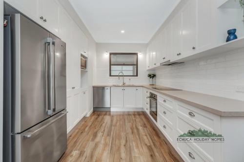 a kitchen with white cabinets and a stainless steel refrigerator at Campaspe Central - Your Central Echuca Escape! in Echuca