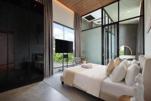 Schlafzimmer mit einem großen weißen Bett und Glaswänden in der Unterkunft Alex Villas Complex N2 in Canggu