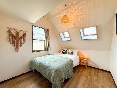 a small bedroom with a bed and two windows at #43 Sajima nagi in Yokosuka