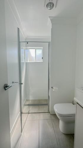 a white bathroom with a shower and a toilet at The Mill Inn Tavern in Millmerran