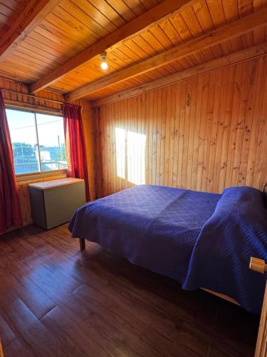 a bedroom with a blue bed in a wooden room at Cabañas Mc Chelo in Pelluhue