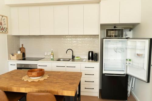 a kitchen with a wooden table and a black refrigerator at Vineyard Villa in McLaren Vale