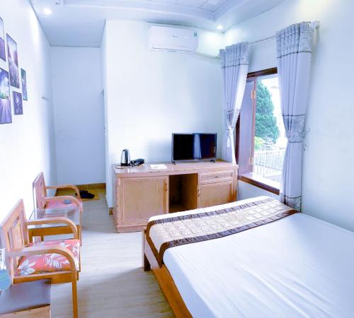 ein Schlafzimmer mit einem Bett, einem Fernseher und einem Fenster in der Unterkunft The Gold House Tam Đảo in Tam Ðảo