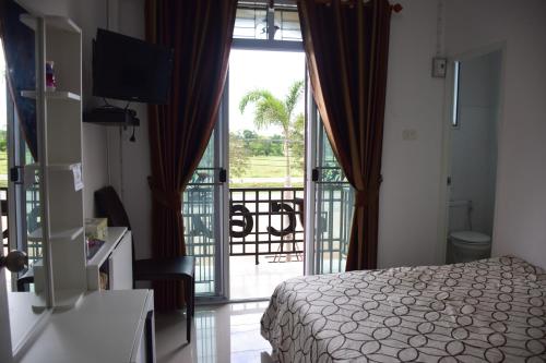 a bedroom with a bed and a balcony with a view at JC Guesthouse @ Suratthani Airport in Surat Thani