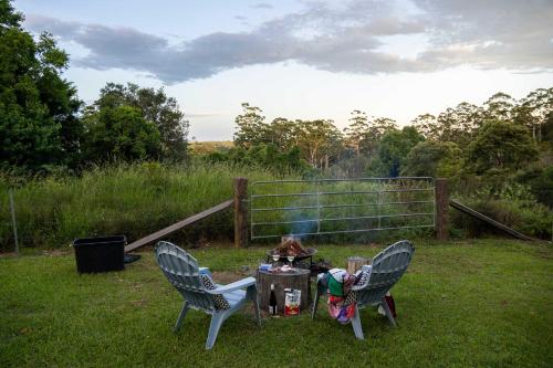 马莱尼White Jacaranda Tiny House by Tiny Away的草地上的两把椅子和一张桌子