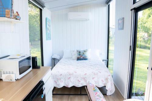 a small bedroom with a bed and a tv at White Jacaranda Tiny House by Tiny Away in Maleny