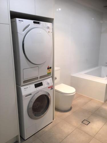 a bathroom with a washing machine and a toilet at Maylands Cottage in Evandale