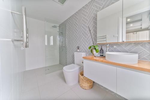 Un baño con inodoro, lavabo y ducha. en 5min to CBD and Sleeps 9 with Spa and EV charger, en Quarry Hill