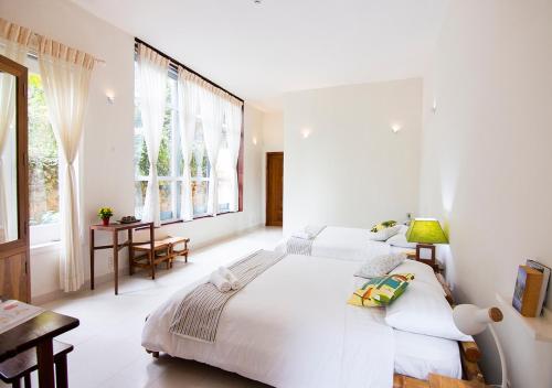una camera bianca con due letti e un tavolo di Lu Tan Residence a Da Lat