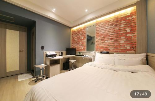 Un dormitorio con una cama y una pared de ladrillo. en KANU hotel, en Seúl