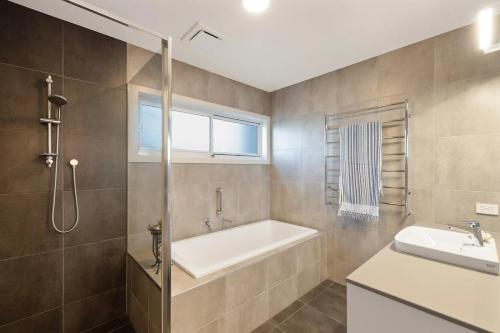 a bathroom with a bath tub and a sink at EcoHaven Beach Retreat in Cape Paterson
