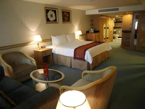 Kampong KiulapにあるThe Rizqun International Hotelの大きなベッドと椅子が備わるホテルルームです。